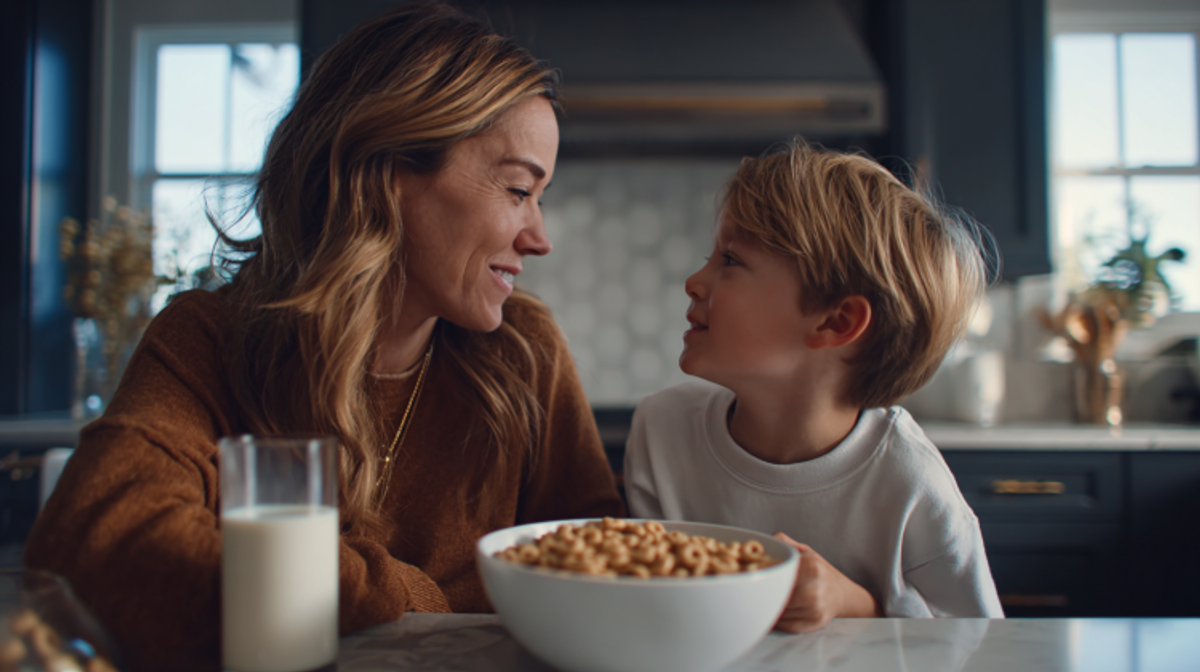 Mother and son smiling over breakfast cereal.
