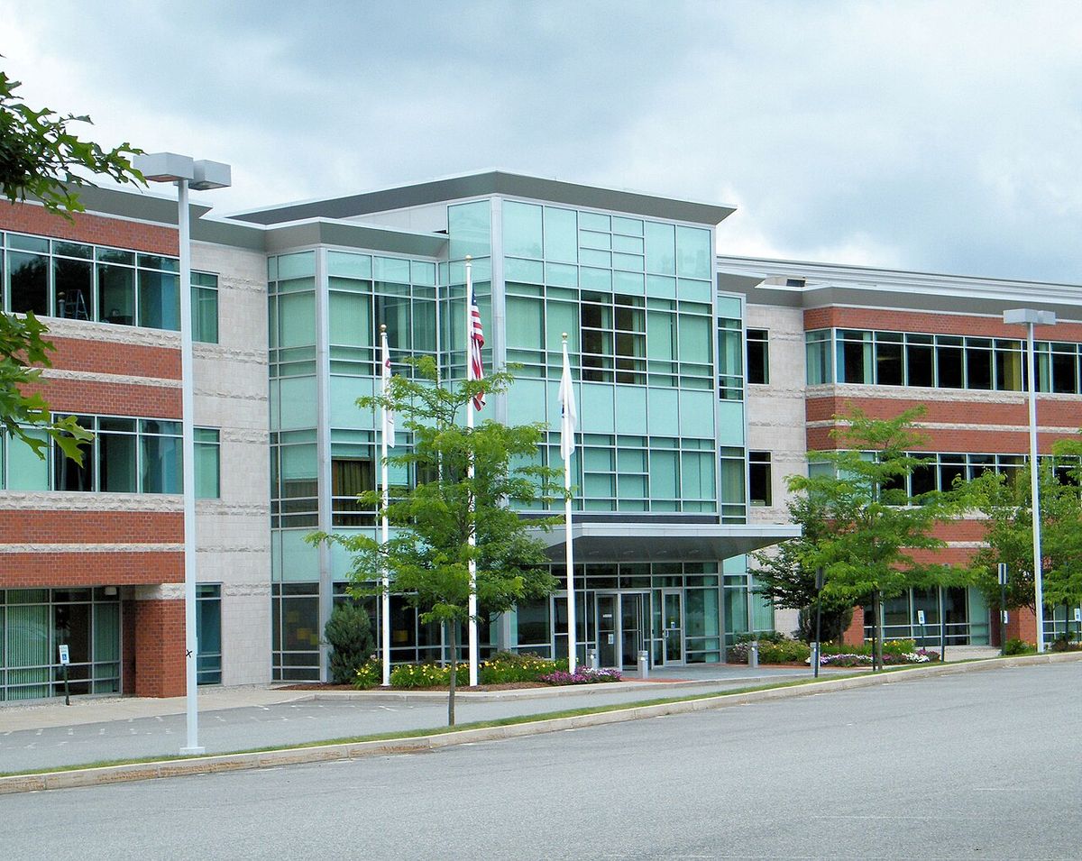 Three-story glass and brick office building with flagpoles out front, the Dunkin' Brands headquarters in Canton, Massachusetts