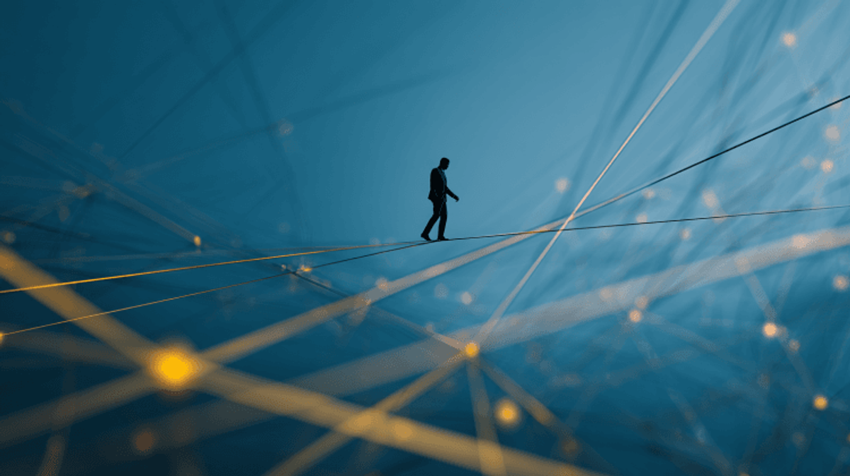 Silhouette walking on a tightrope amid blue network.