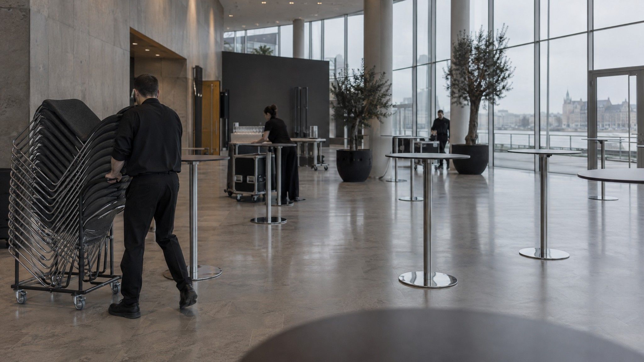 Conference foyer being set up with bare cocktail tables and stacked chairs