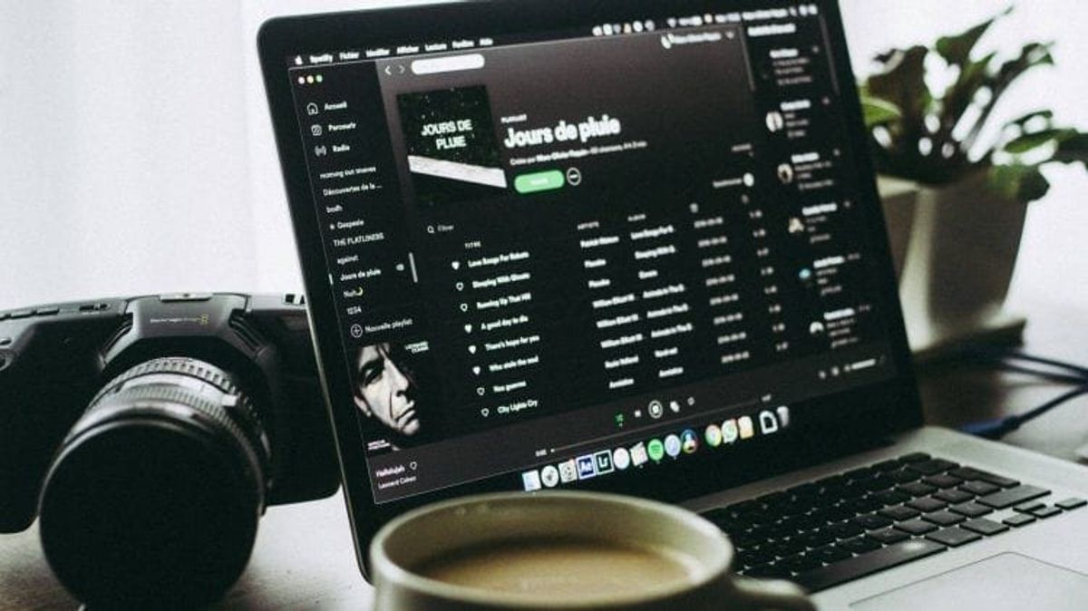 Laptop playing Spotify music playlist next to camera