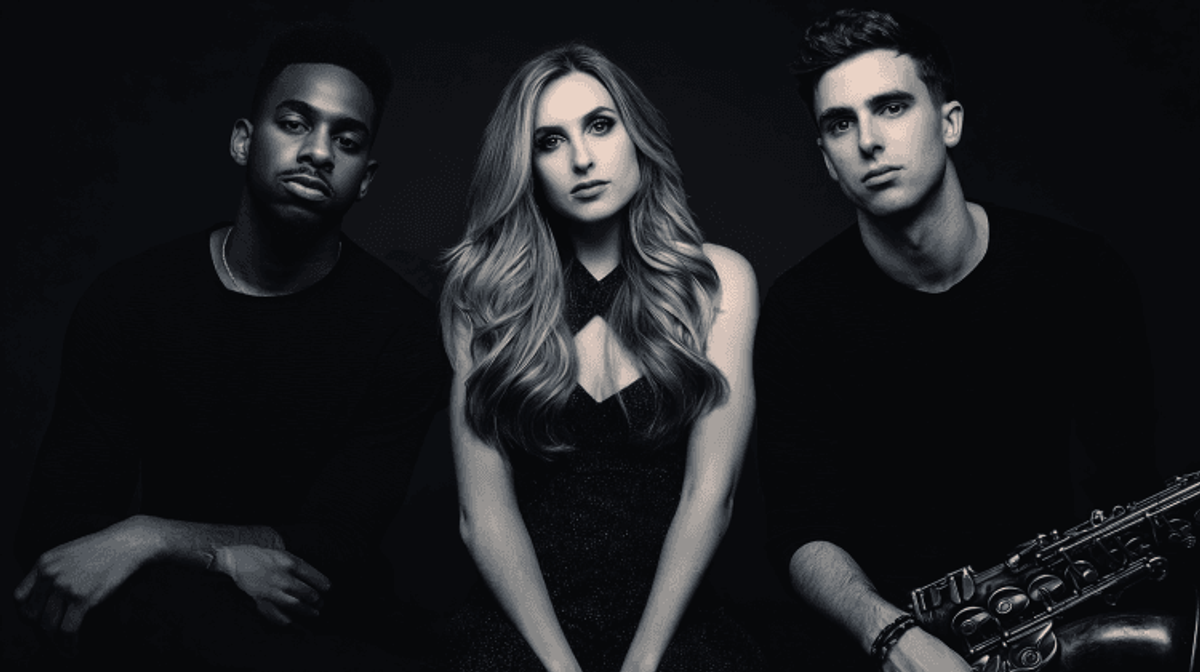 Three individuals posing with a saxophone.