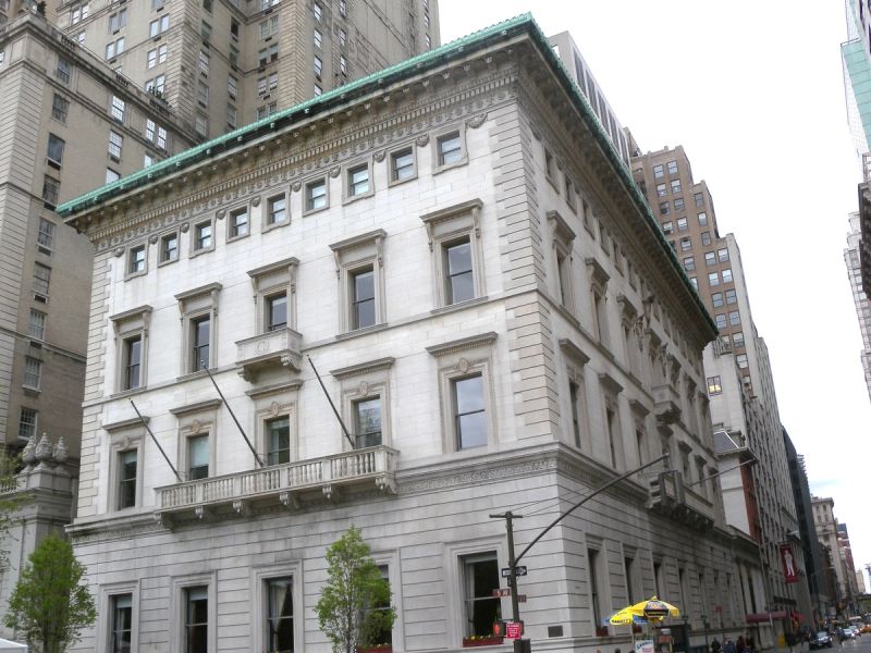 The Metropolitan Club's white marble clubhouse at Fifth Avenue and 60th Street, with a balcony above the ground floor and a green copper cornice, seen from the street corner