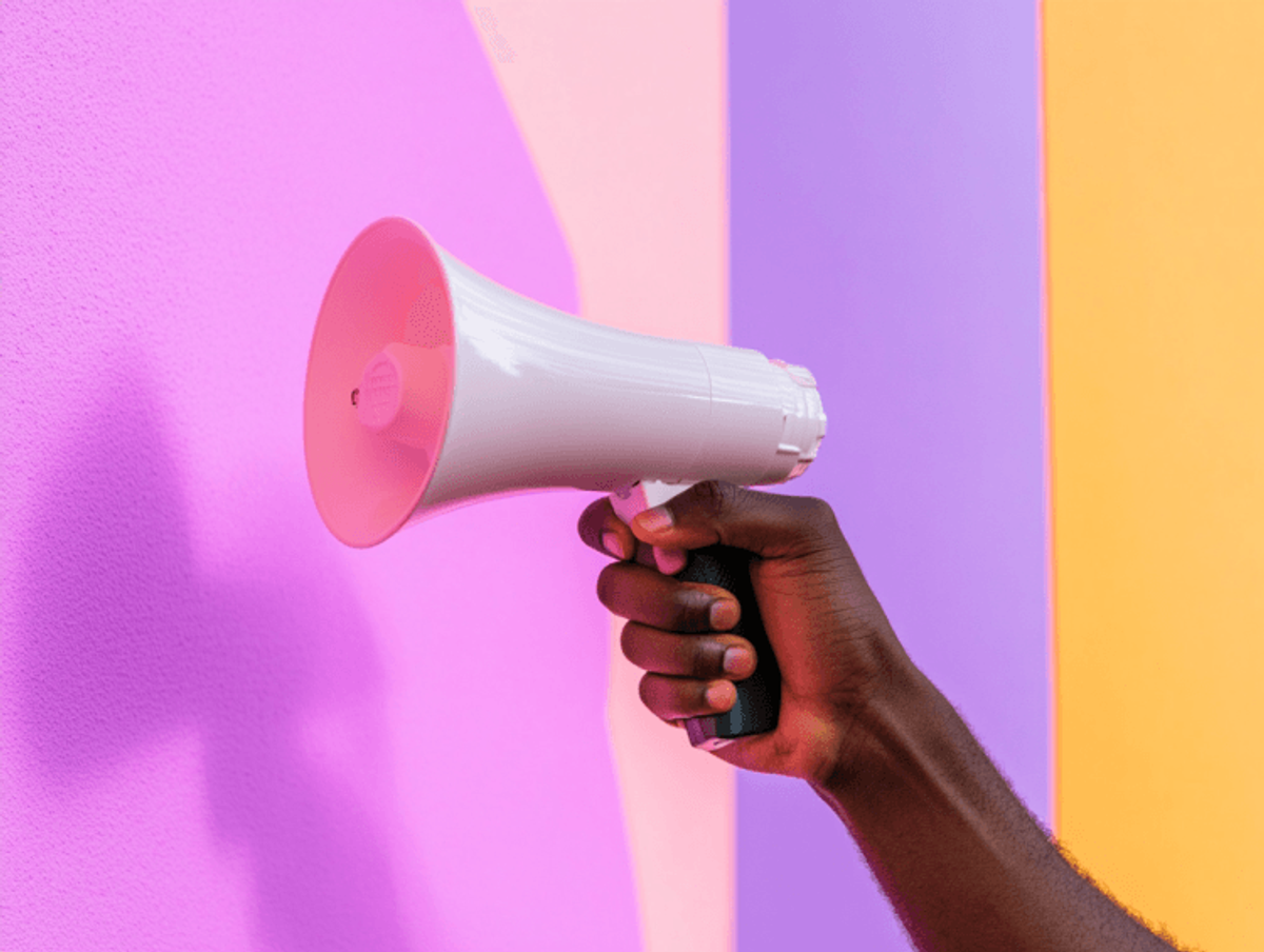 Hand holding megaphone against colorful background
