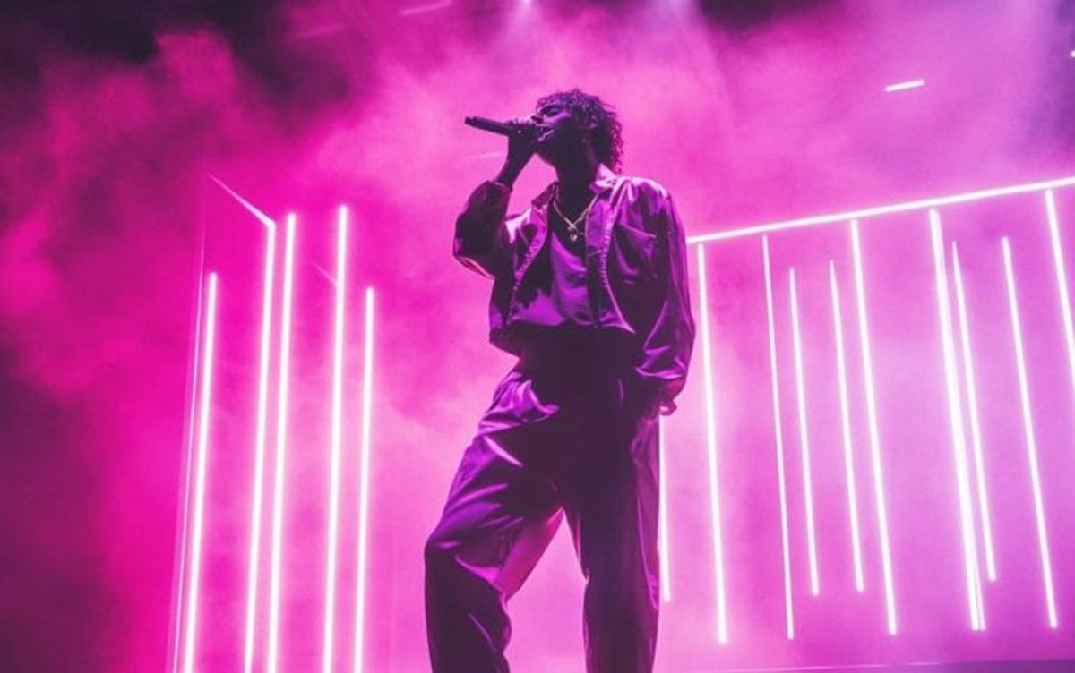 Singer performing on stage with pink lighting