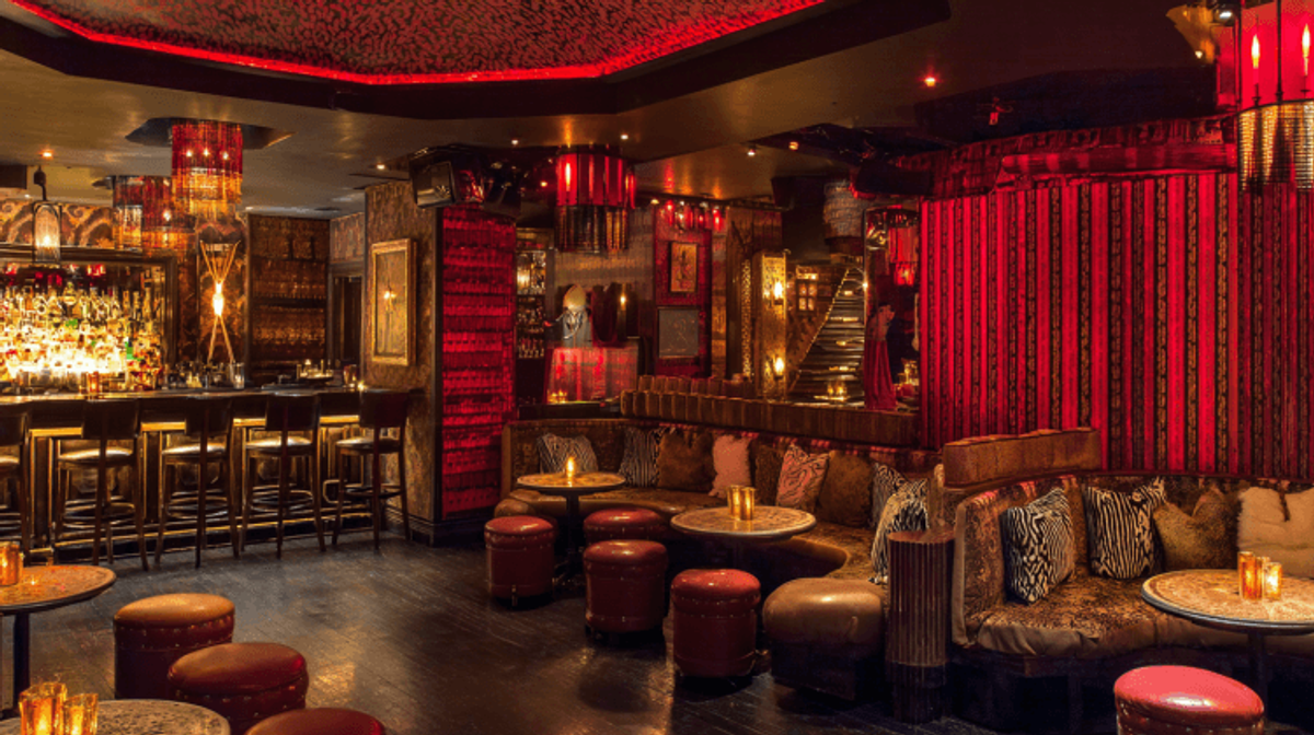 Luxurious bar with plush seating and red lighting.