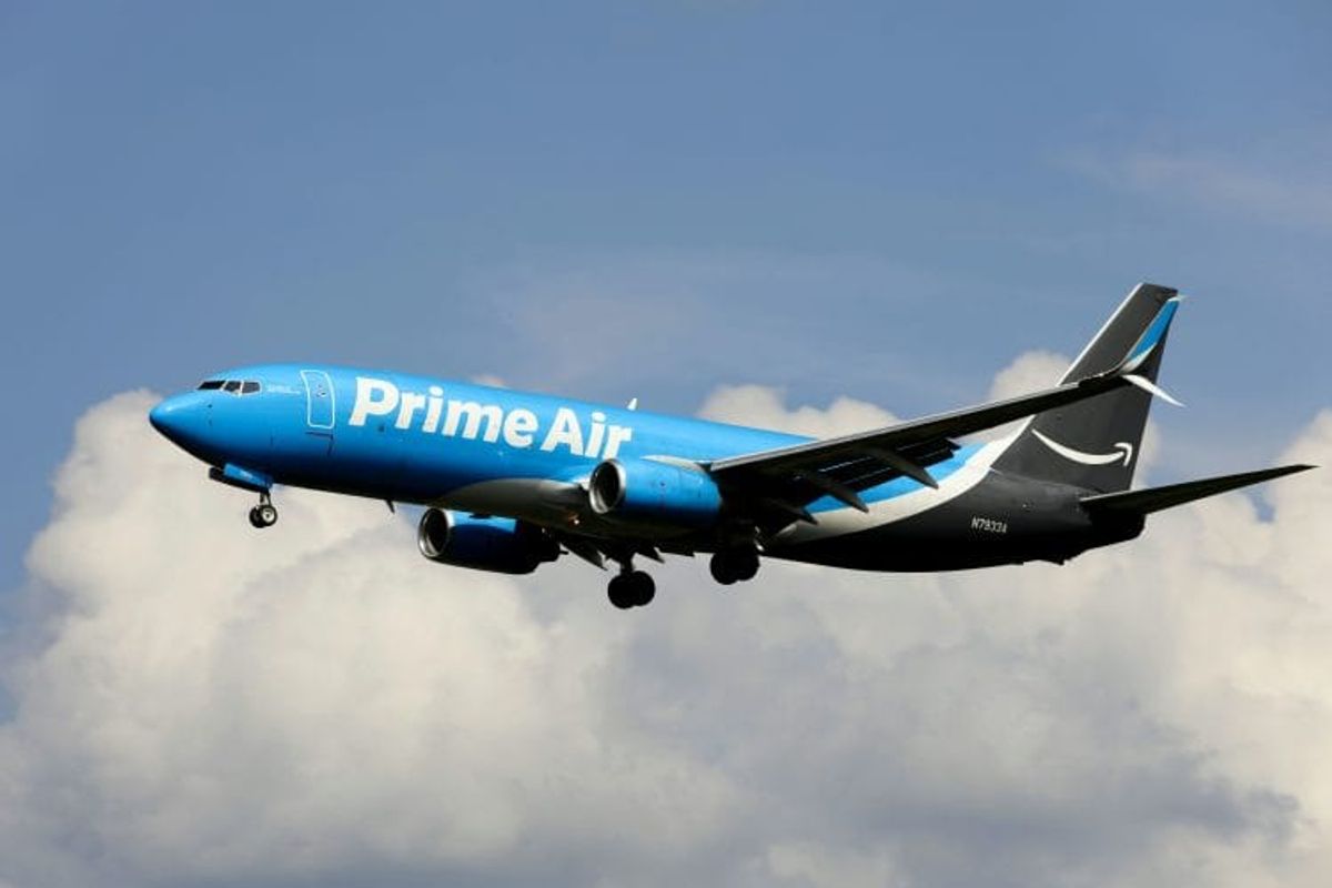 Amazon Prime Air plane in flight, cloudy sky background.