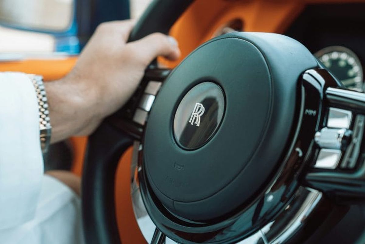 Close-up of hand on luxury car steering wheel.