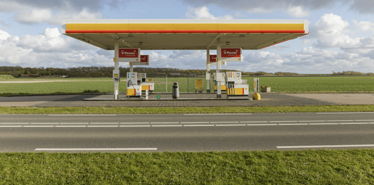 Rural gas station with green fields background.