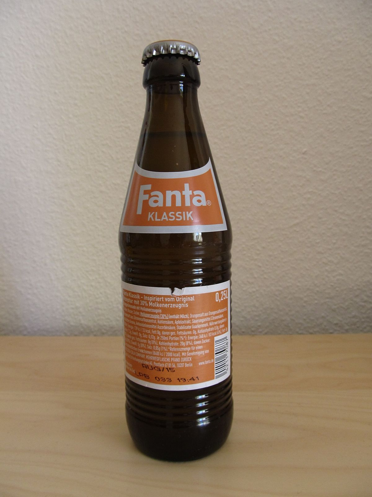 A brown ribbed Fanta Klassik glass bottle seen from the back, with an orange label listing ingredients