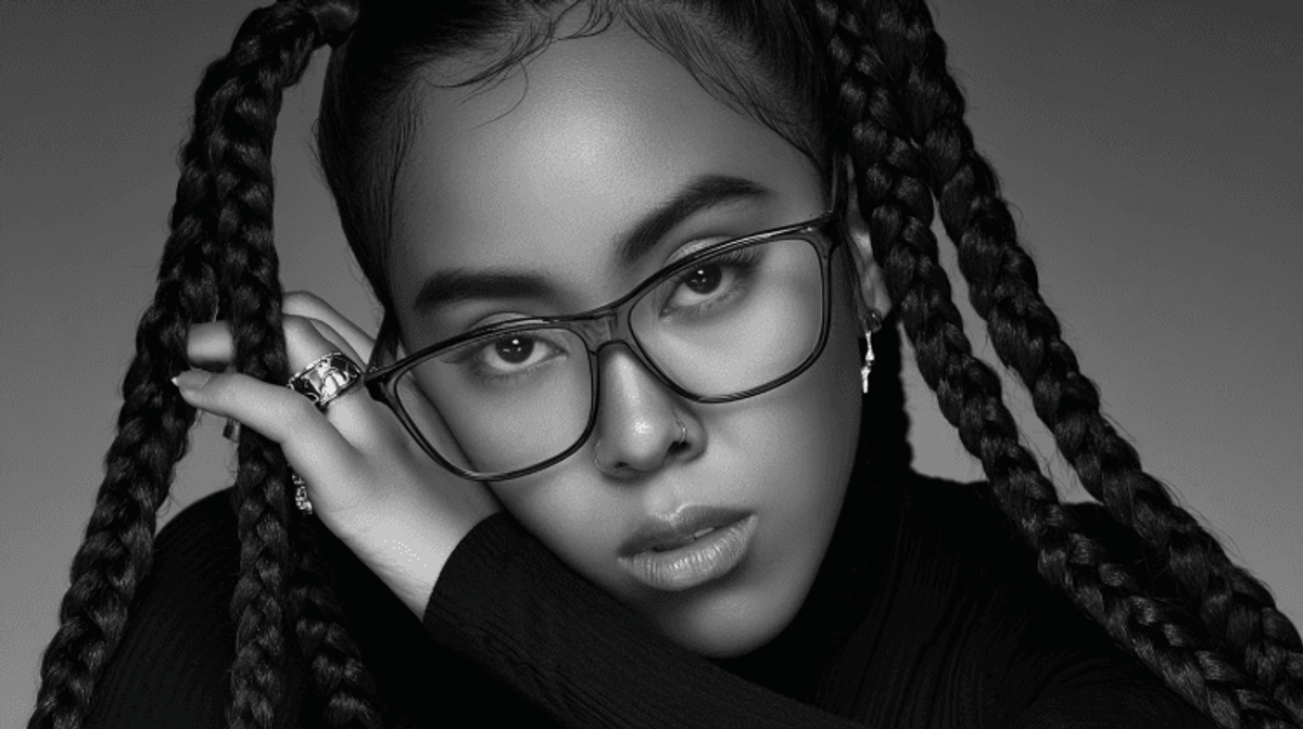 Woman with glasses and braided hair, serious expression.