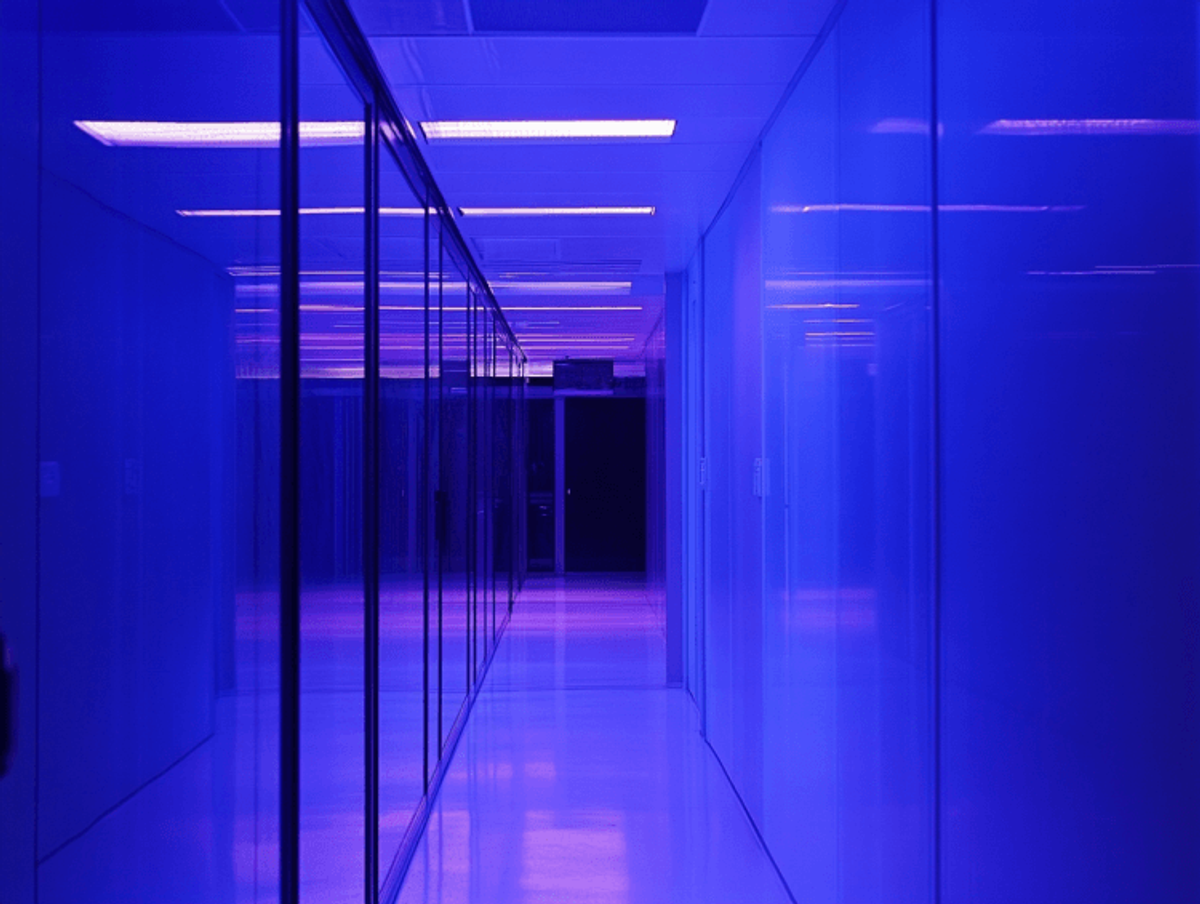 Blue-lit hallway with glass walls and reflections