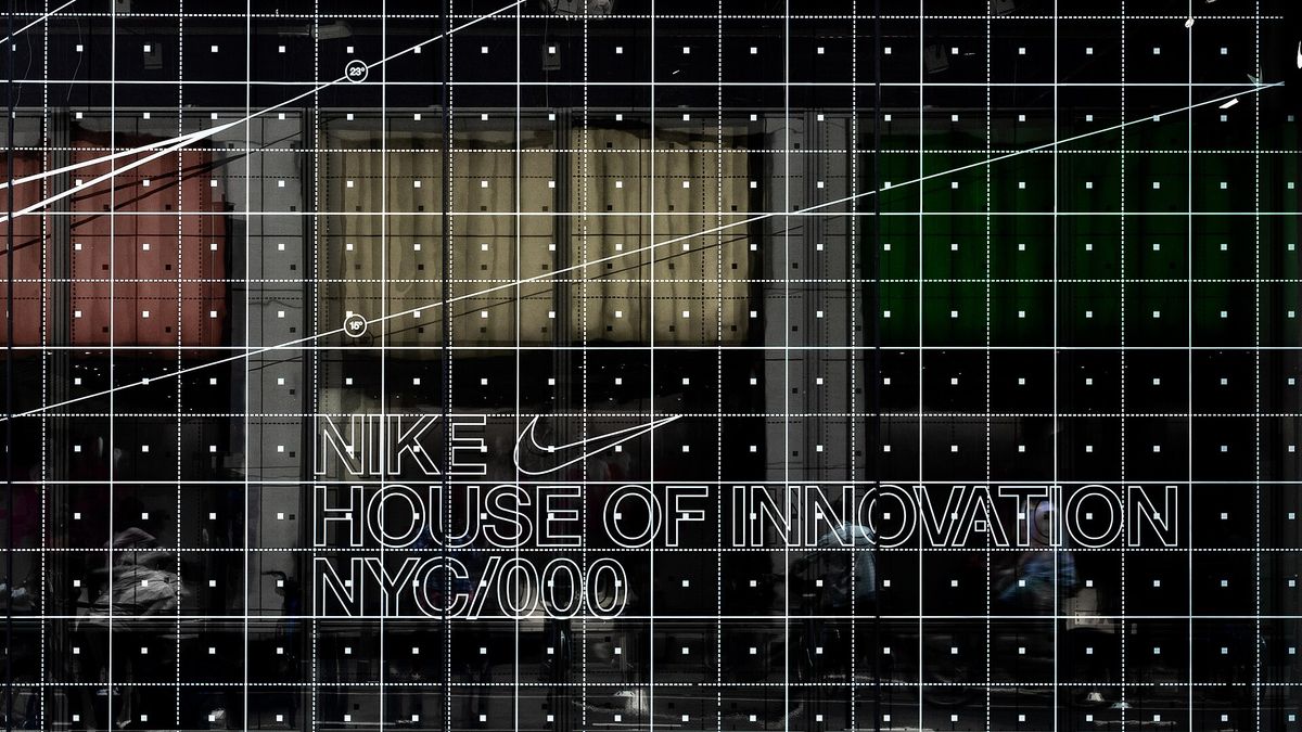 The glass front of Nike's House of Innovation store in Manhattan, printed with a white grid and the words NIKE HOUSE OF INNOVATION NYC/000 beside a small swoosh