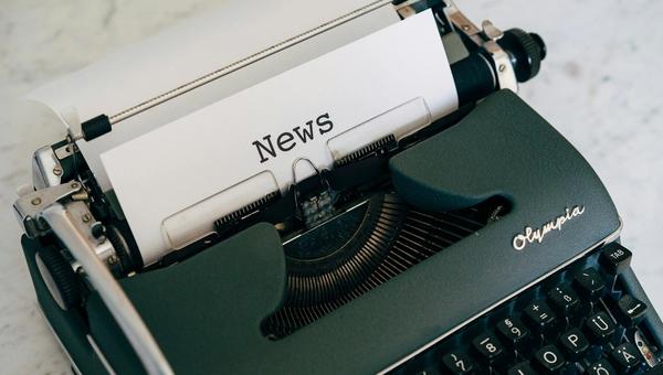 Stack of newspapers and media publications on a wooden surface