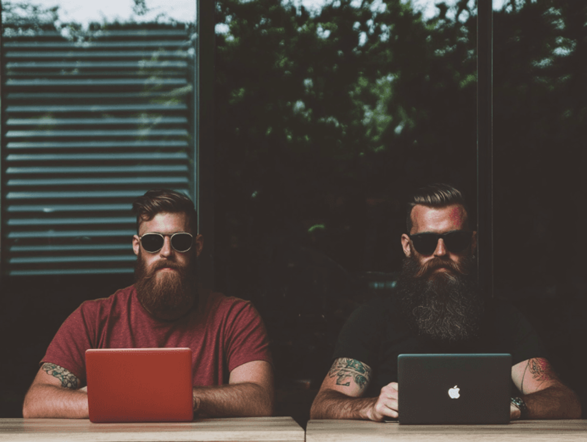 Two men using laptops indoors.