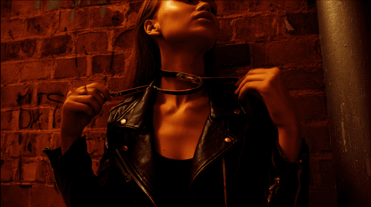 Person wearing a leather jacket against brick wall.
