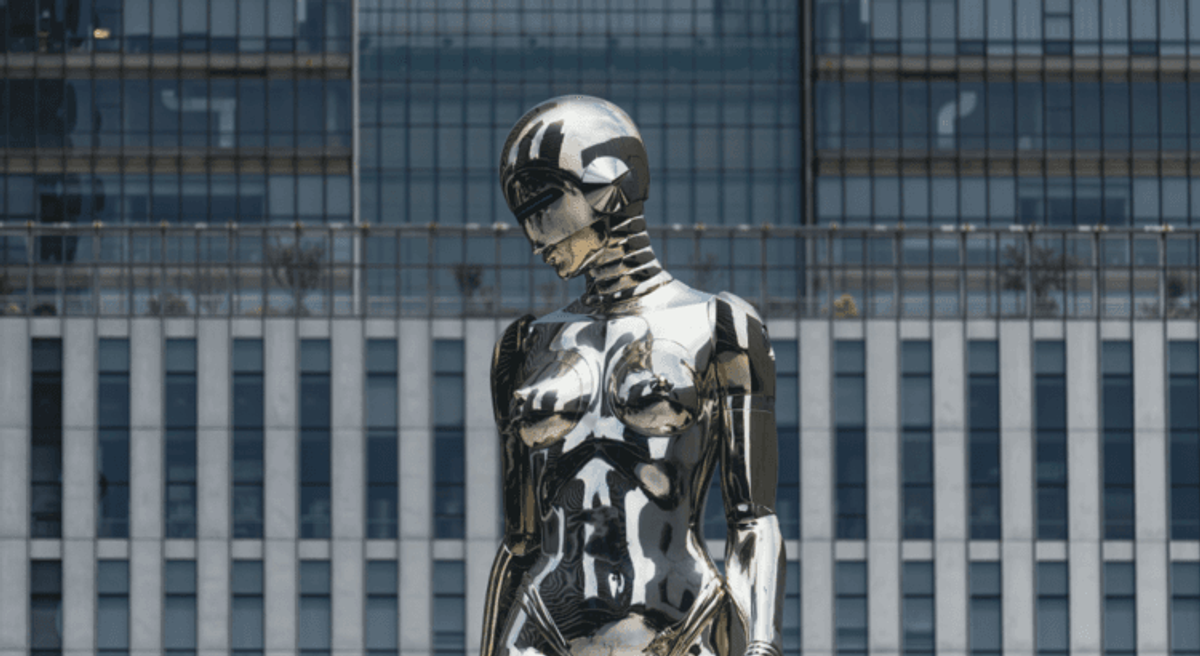 Futuristic chrome robot sculpture in urban setting.