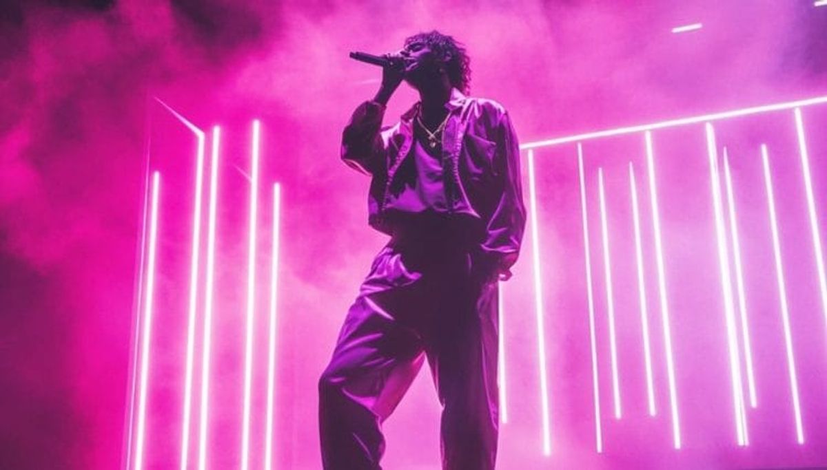 Singer performing on stage with neon lights.