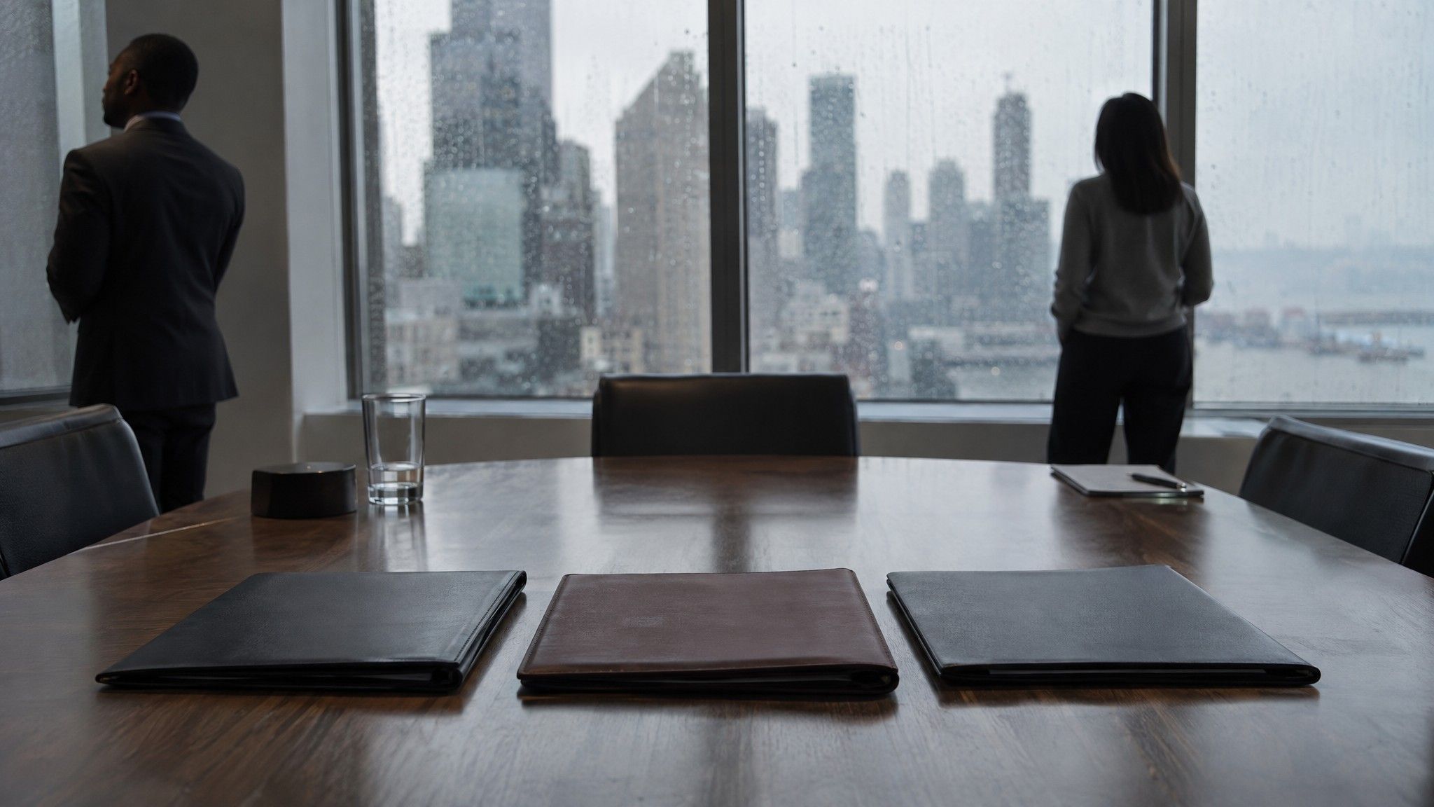 Three closed folders side by side on a conference table