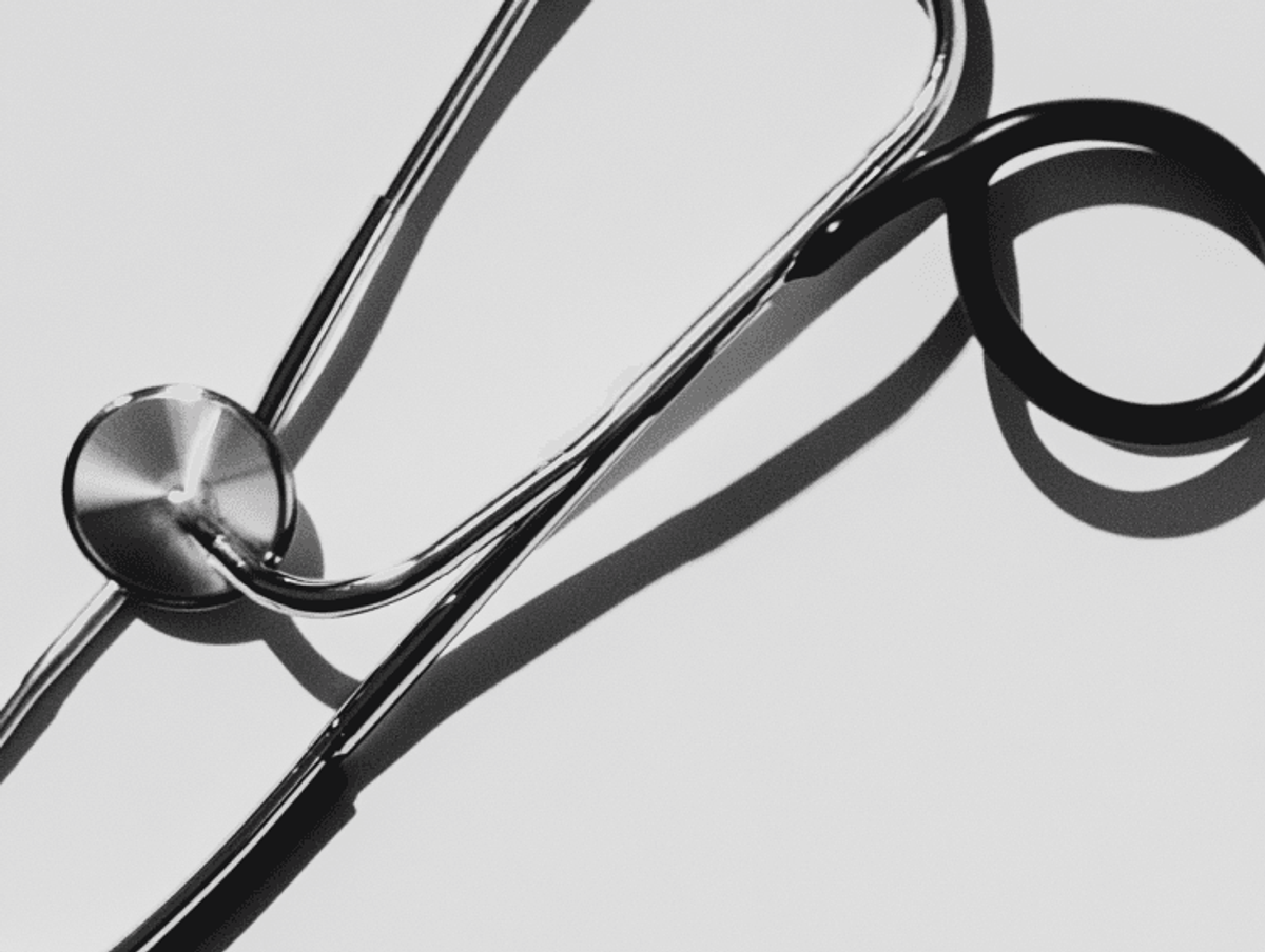 Silver stethoscope casting shadow on white surface.
