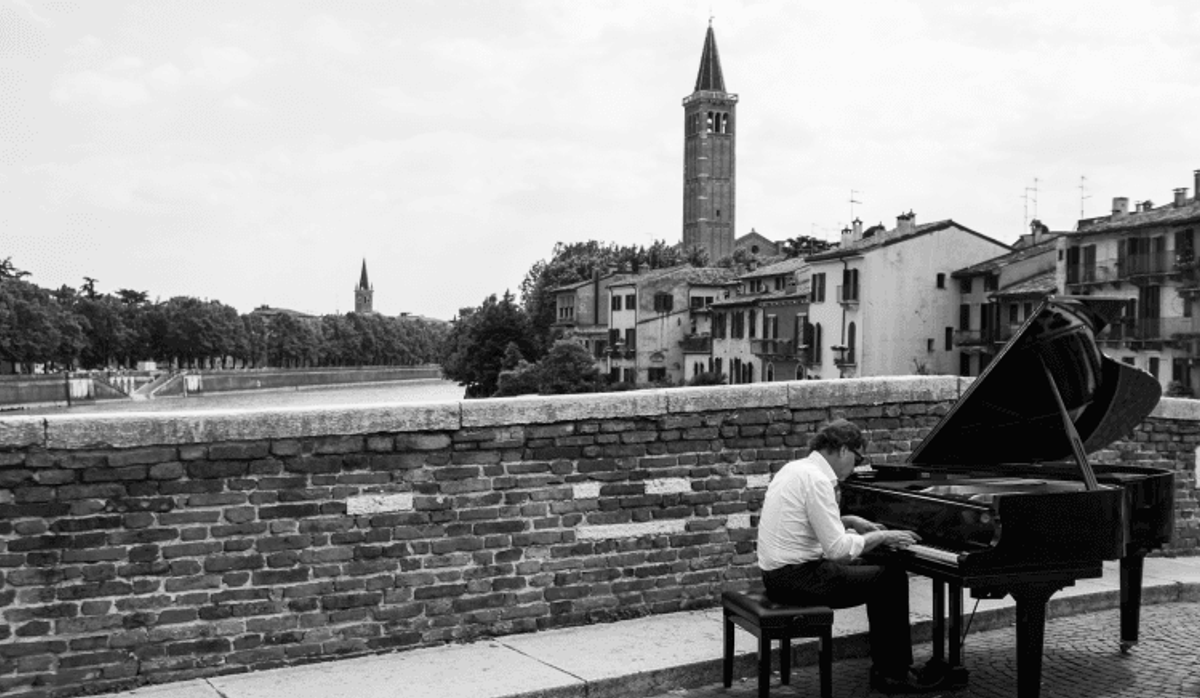 Man playing piano on a city bridge