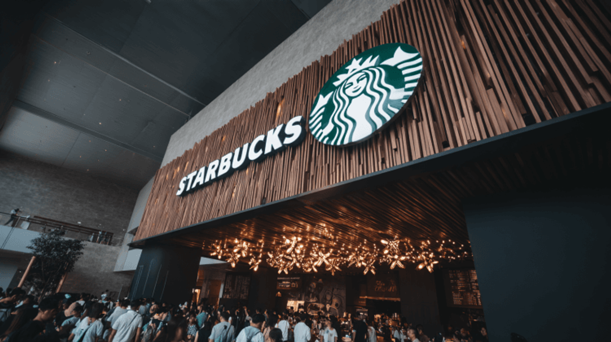 Crowded Starbucks with wooden decor and lighting.