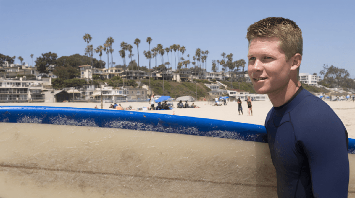 Surfer carrying board on sunny beach