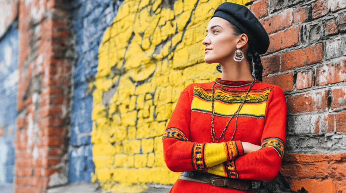 Person in colorful sweater against brick wall