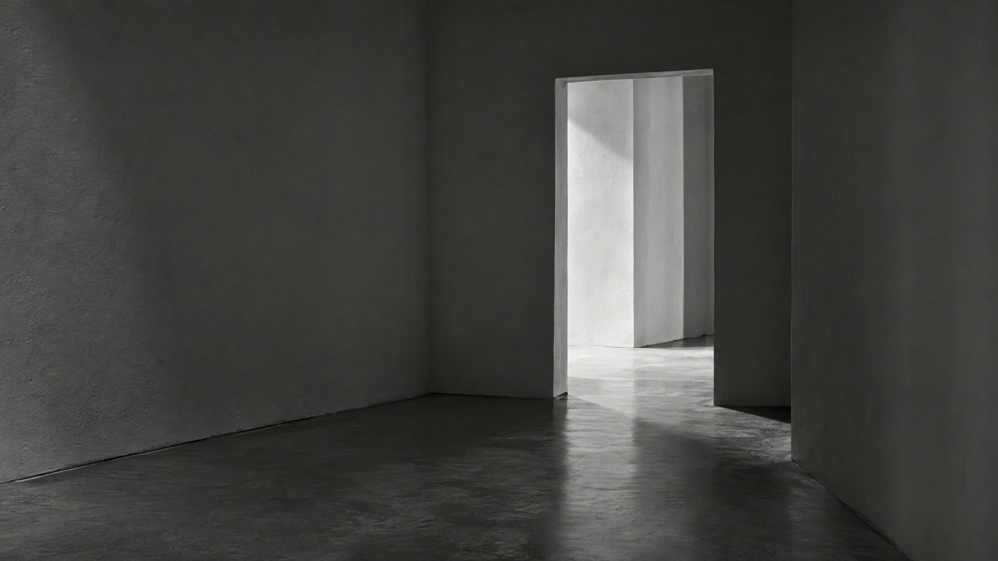 Empty concrete corridor ending in an open doorway with light