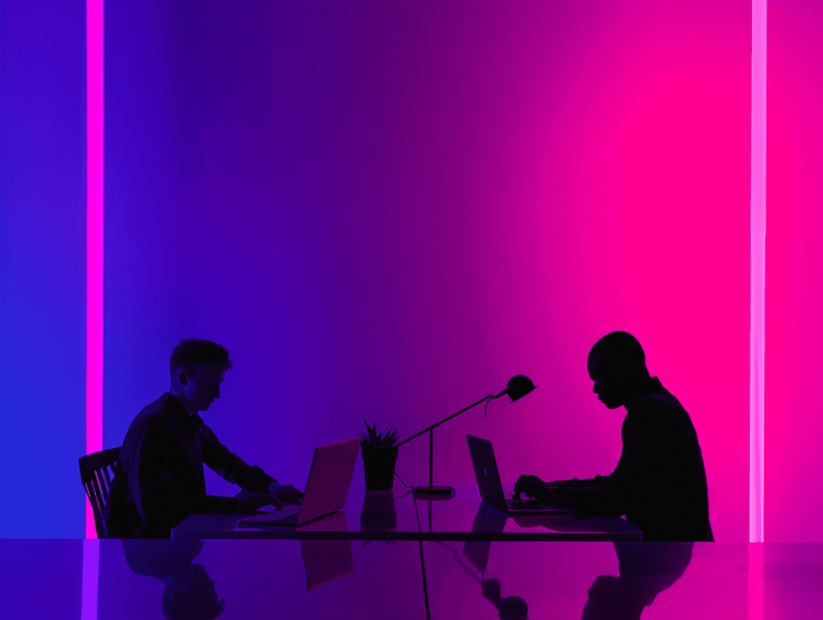 Silhouetted people working on laptops in colorful lighting.