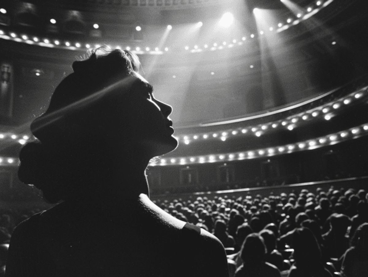 Silhouetted woman facing a lit concert hall audience.
