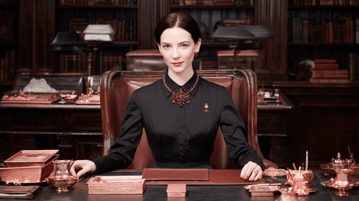 Woman in ornate office with copper decor.