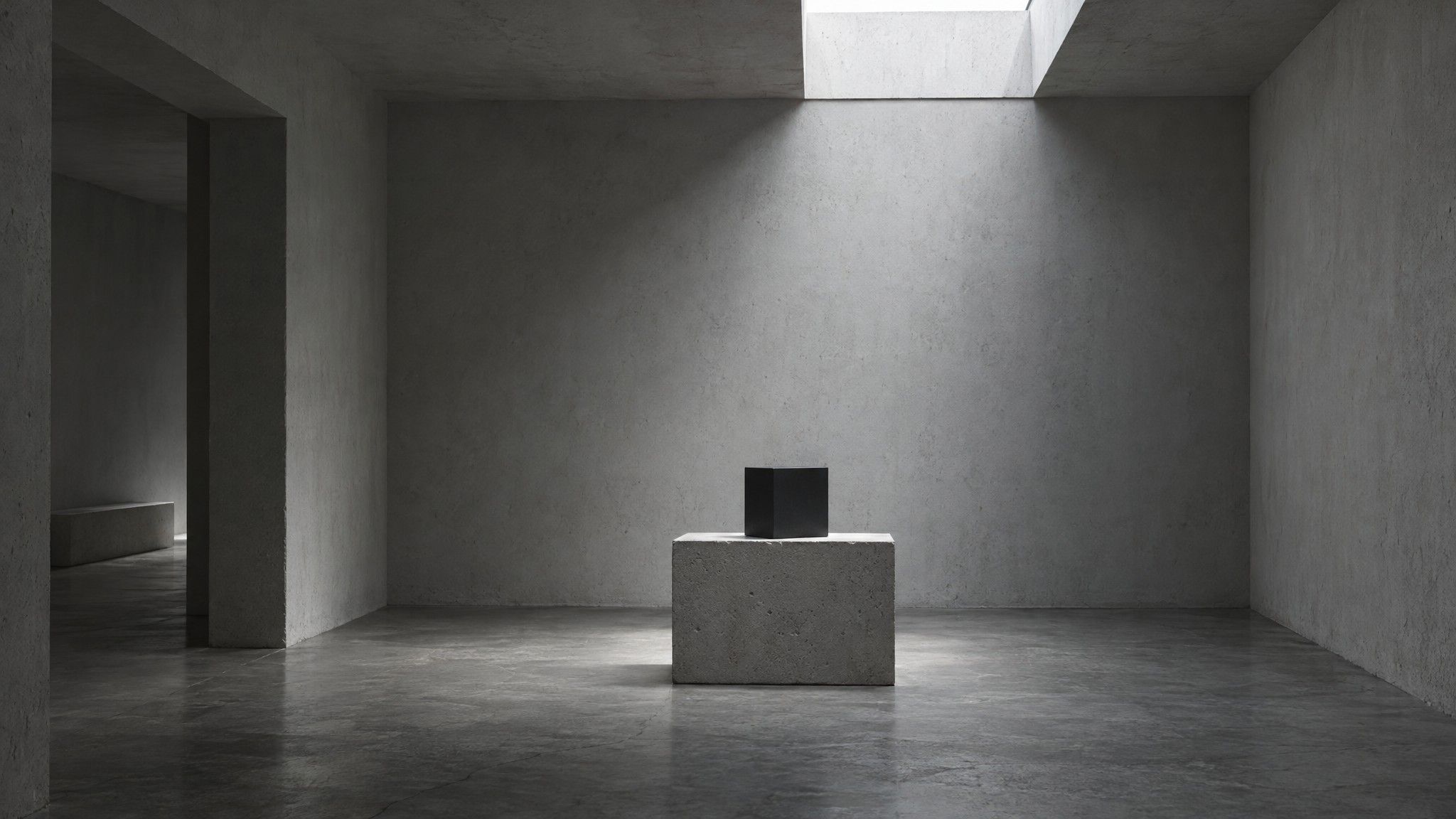 Small black cube on a concrete plinth under a narrow skylight