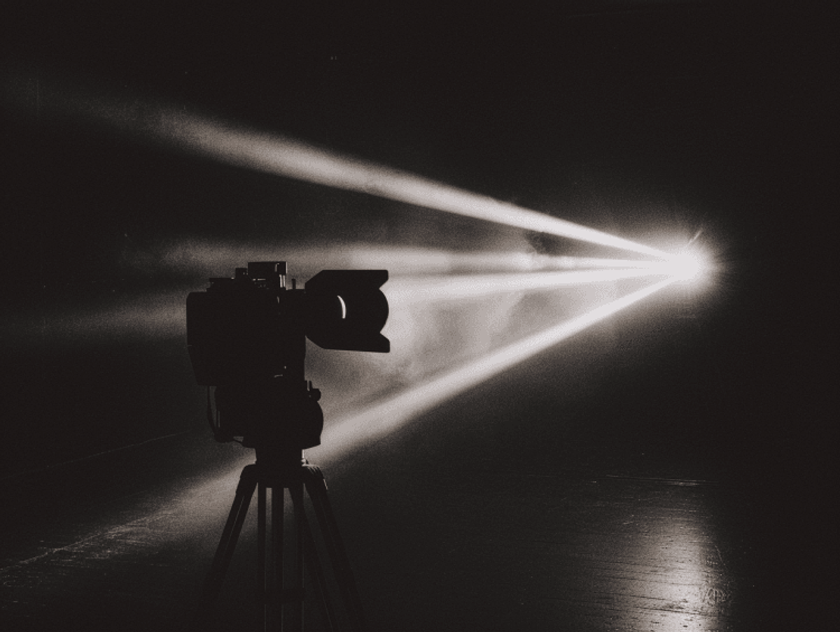 Film projector casting beams of light in dark.