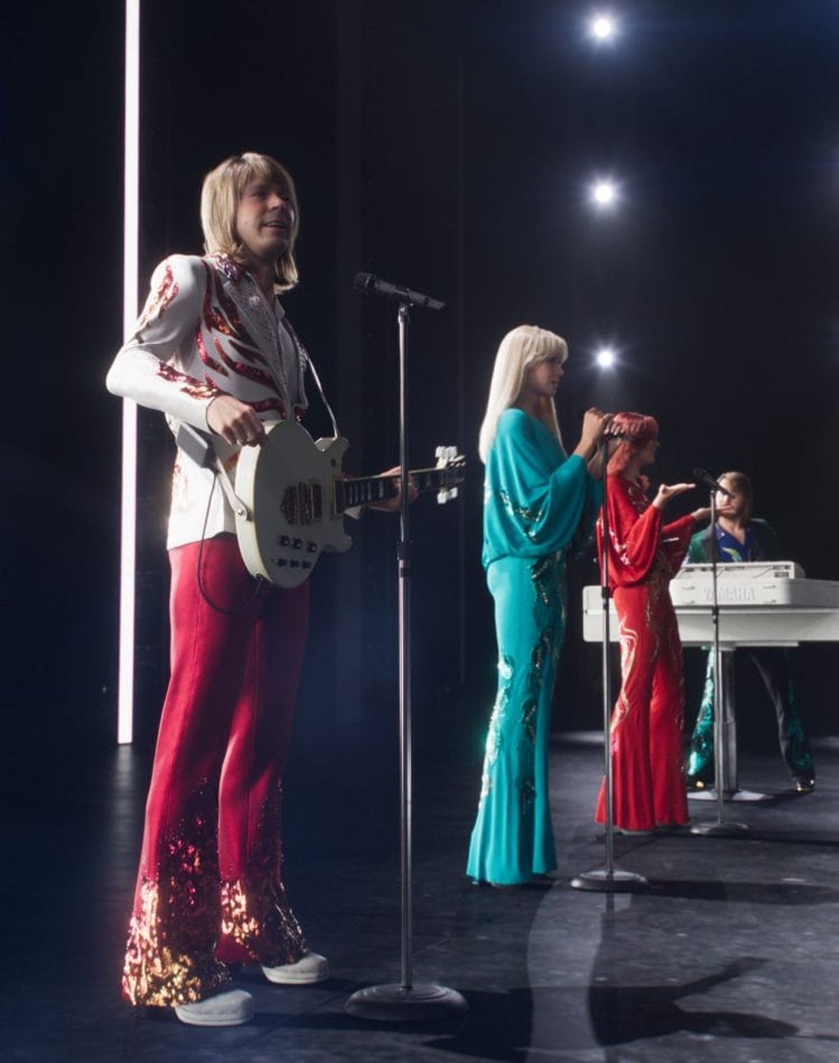 Band performing on stage with instruments and colorful outfits.