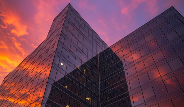 Modern glass office building facade reflecting vivid sunset clouds