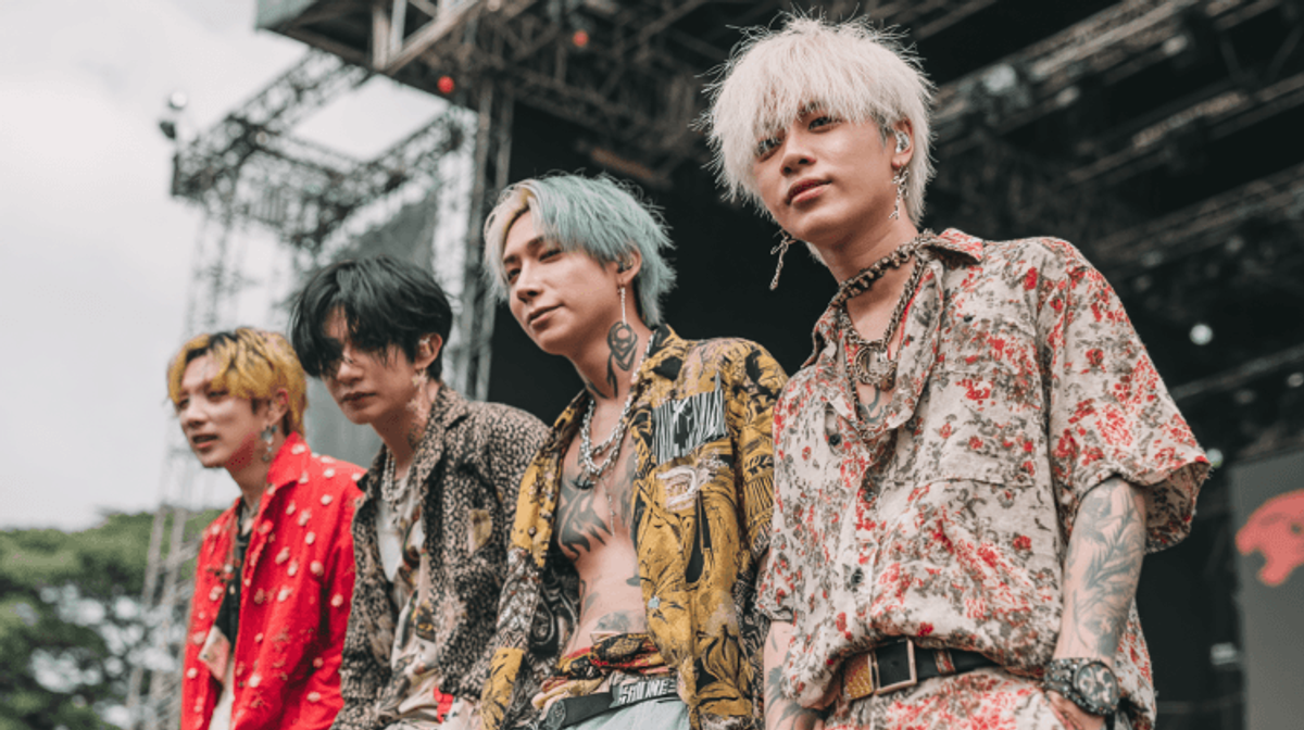 Band members performing on stage in stylish outfits.