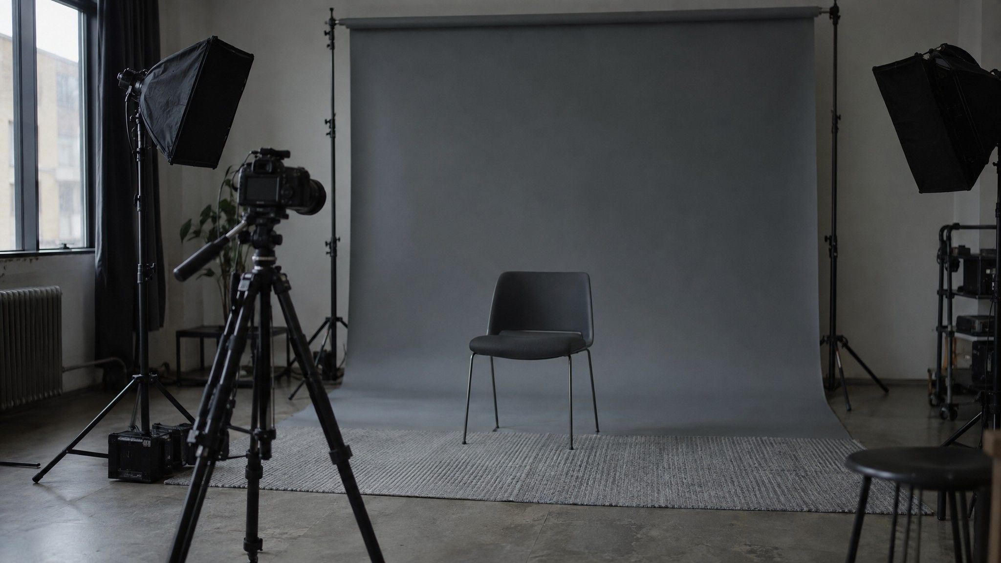 Video studio with a camera facing an empty chair and grey backdrop