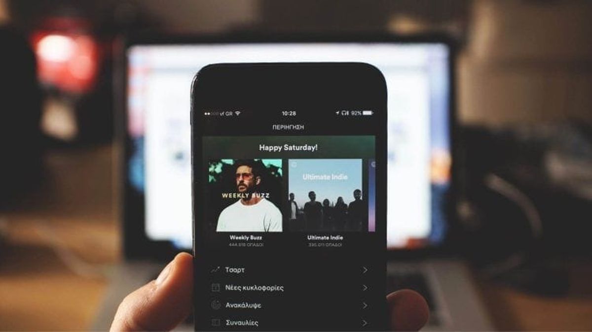 Person holding smartphone with music app open.