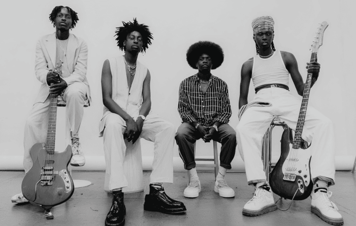 Four musicians posing with electric guitars.
