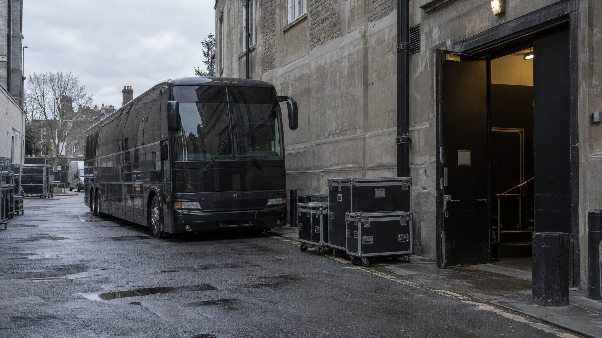 Tour bus behind a theatre with flight cases on the pavement