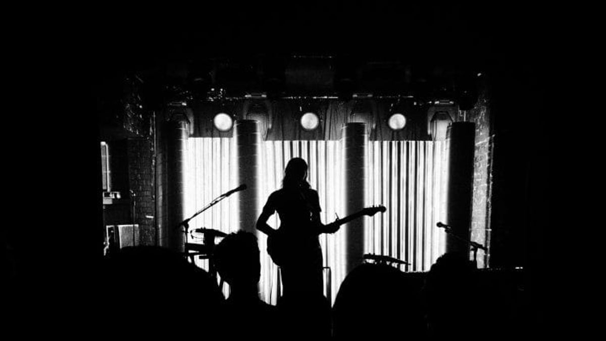 Silhouette of guitarist on stage with crowd.