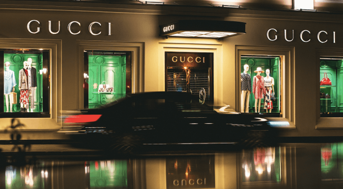 Luxury fashion store with mannequins and passing car.