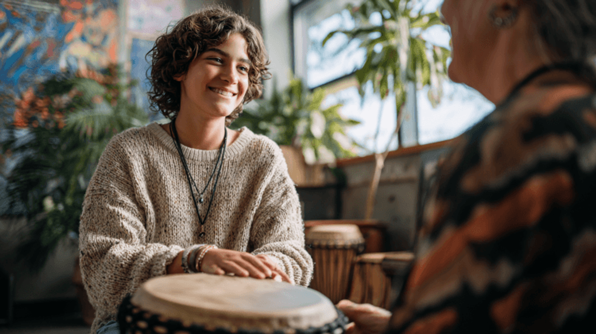 Person playing drums in cozy, plant-filled room.