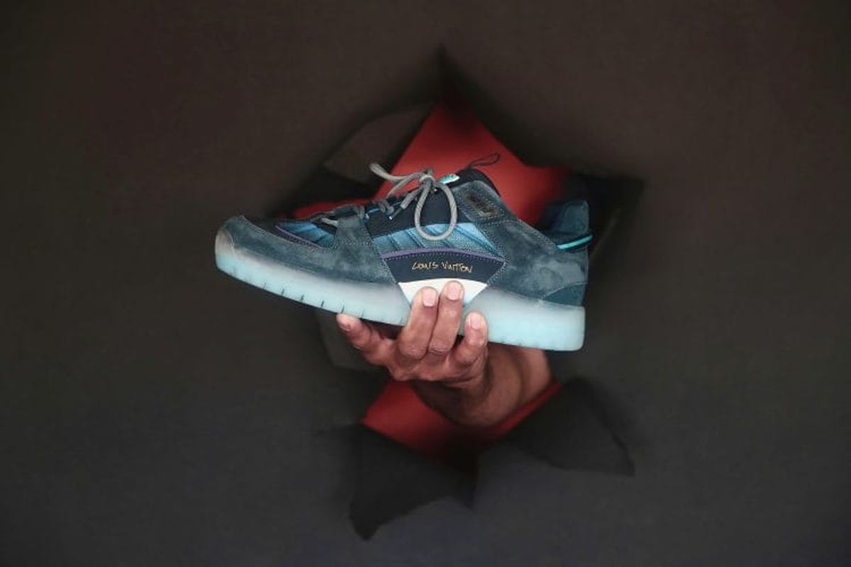 Hand holding designer sneaker through torn paper