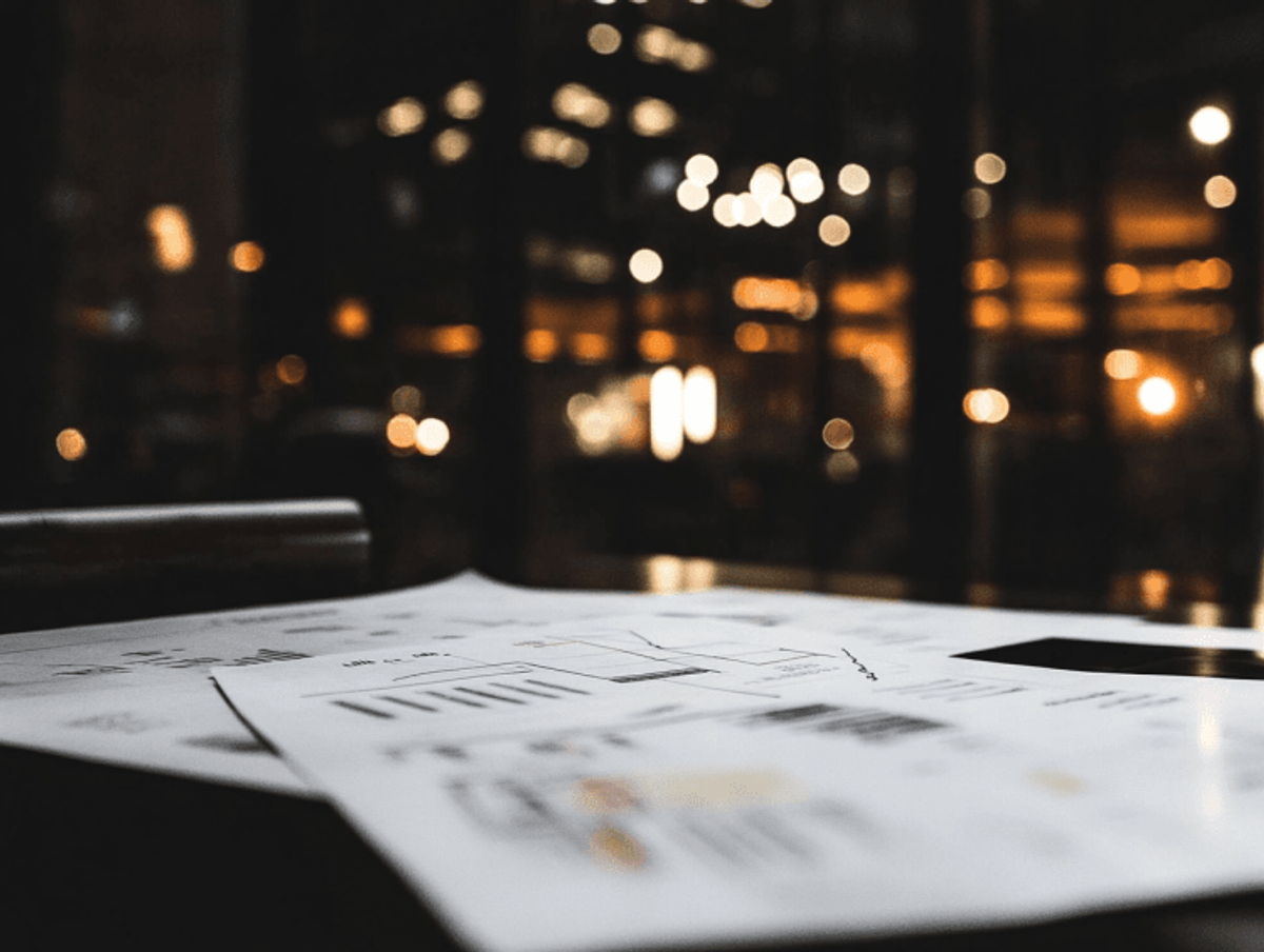 Business documents on desk in dimly lit office.