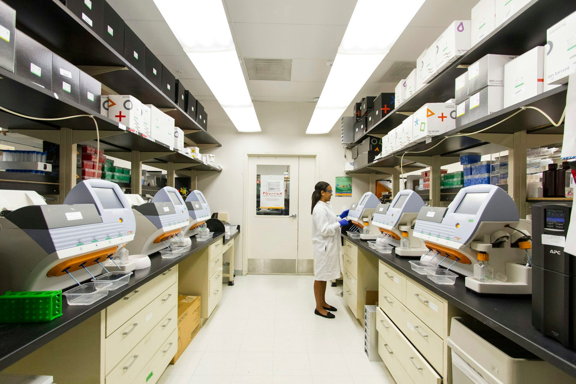 Research scientist working among genomic sequencing instruments in a biotech laboratory