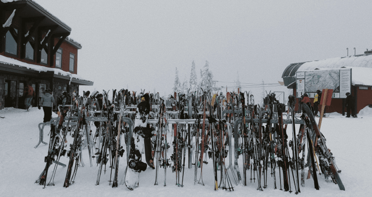 Snowy ski lodge with parked skis and snowboards.