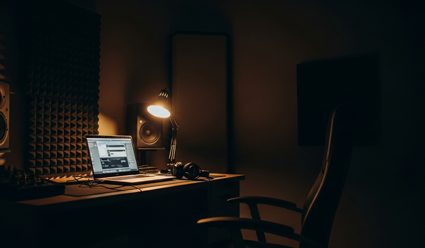 Home recording studio at night with laptop screen glowing and headphones on desk