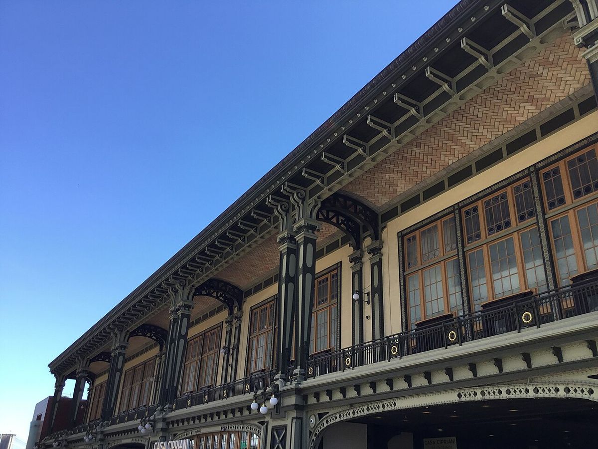 The Battery Maritime Building's dark green columns and herringbone-tiled porch ceiling against a blue sky, with a Casa Cipriani sign at the lower left